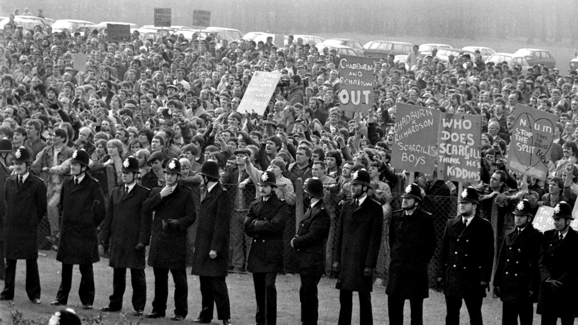 Steikende Bergarbeiter demonstrieren am 1. Mai 1984 im englischen Nottinghamshire gegen die Schließlung von Mienen. Vor ihnen steht eine Reihe von Polizisten. Steikende Bergarbeiter demonstrieren am 1. Mai 1984 im englischen Nottinghamshire gegen die Schließlung von Mienen. Vor ihnen steht eine Reihe von Polizisten.