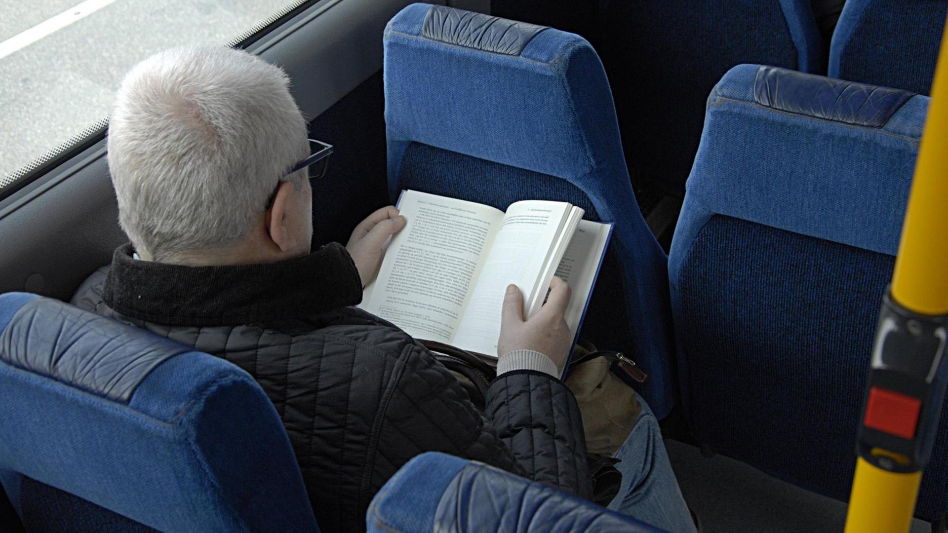 Ein Mann liest in einem Bus ein Buch.