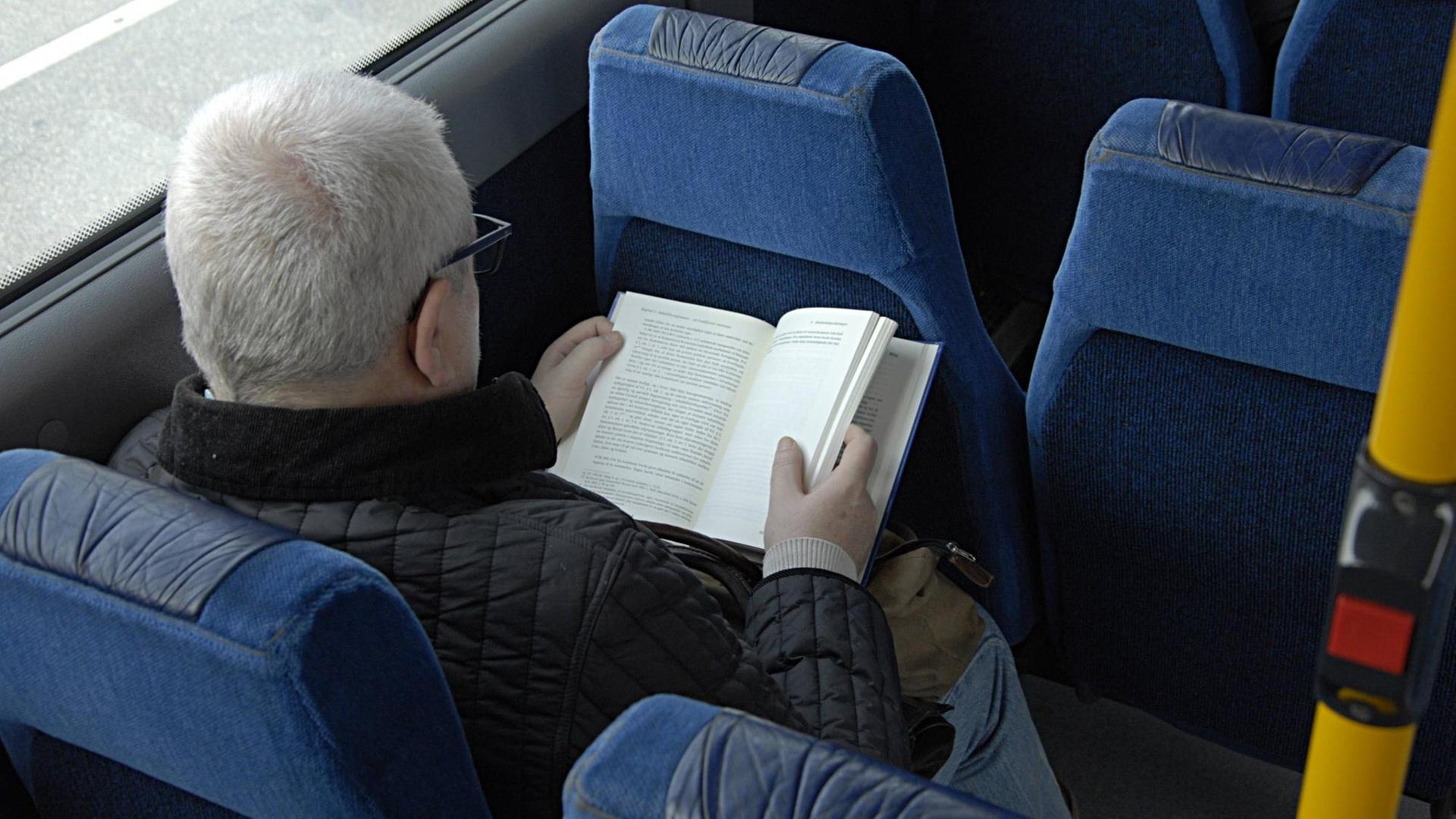 Ein Mann liest in einem Bus ein Buch. Ein Mann liest in einem Bus ein Buch.