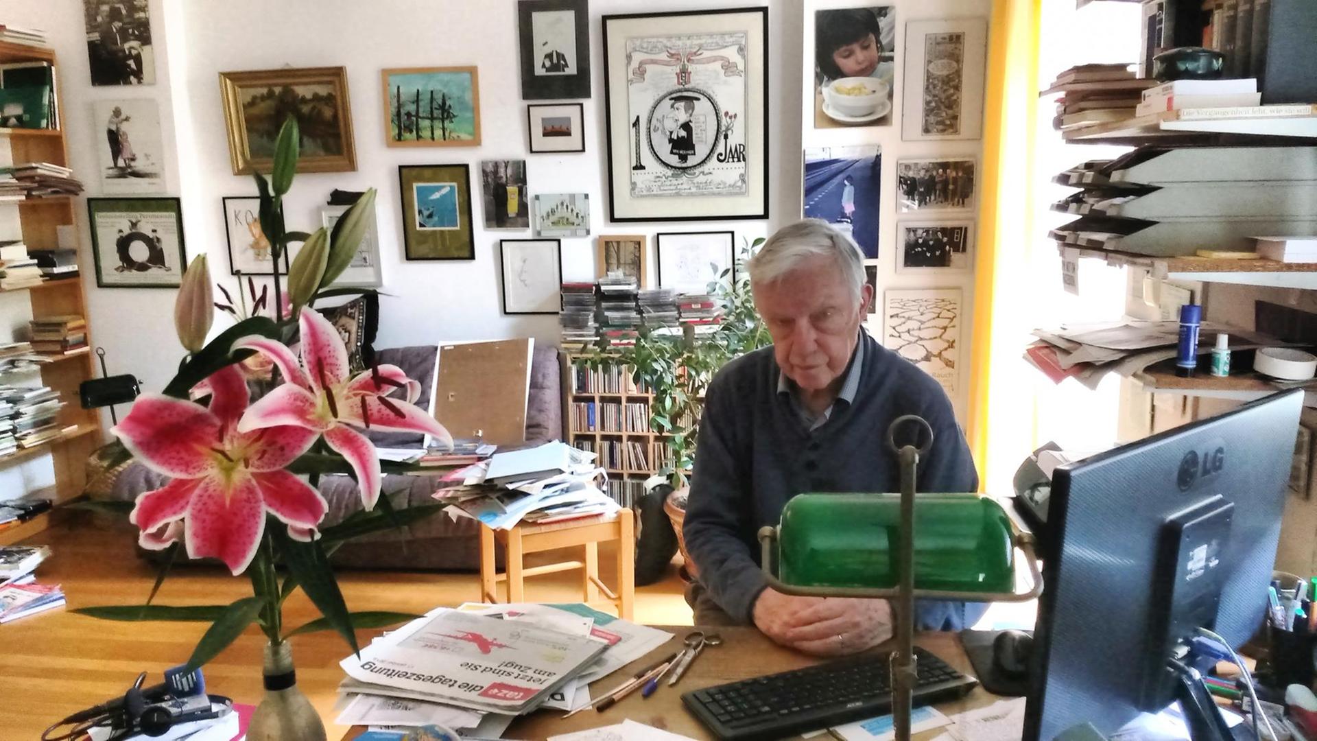 Der Karikaturensammler Koos van Weringh sitzt in seinem Wohnzimmer am Schreibtisch