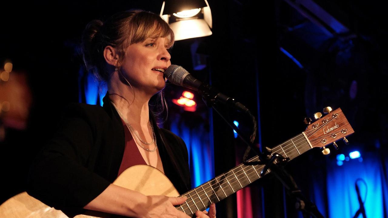 Christina Lux vor einem Mikrofon mit Gitarre Christina Lux vor einem Mikrofon mit Gitarre