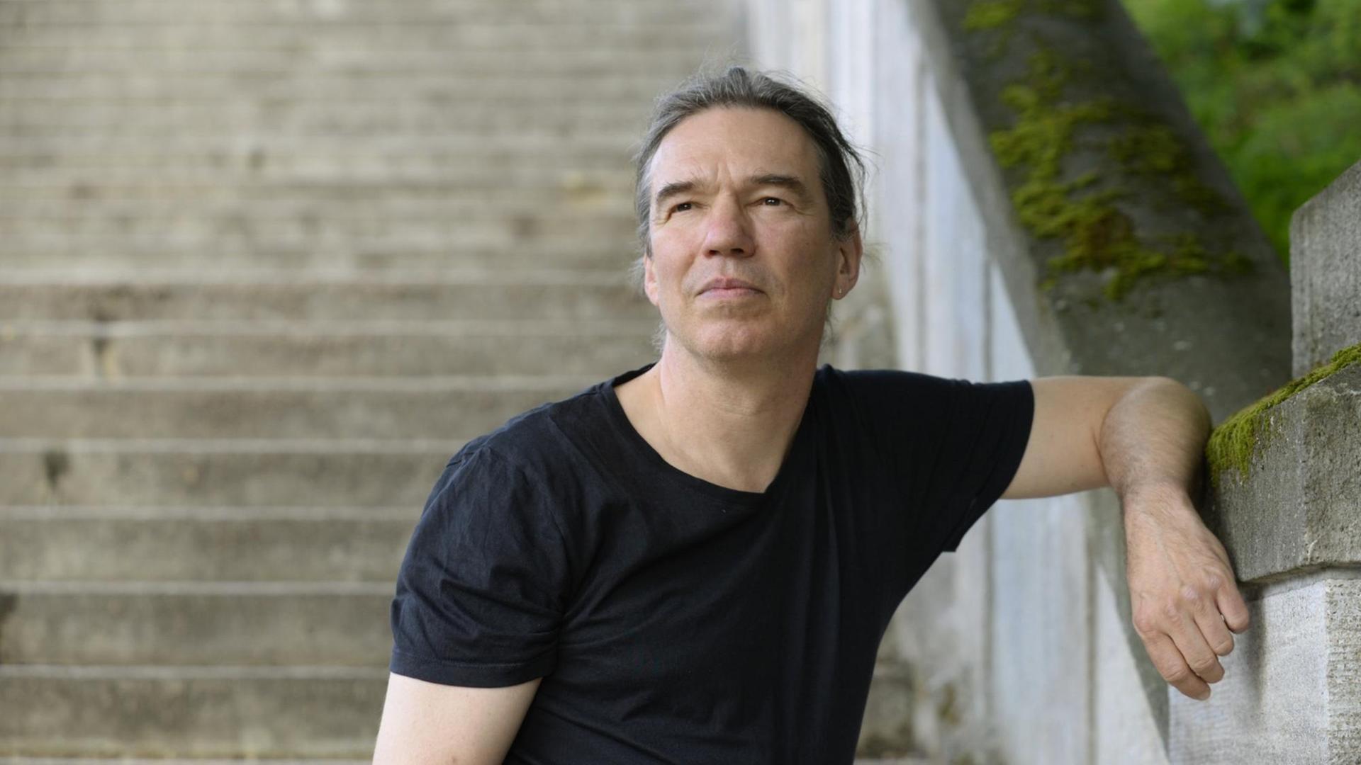 Ein Porträtfoto zeigt Michael Wildenhain, Autor und Schriftsteller angelehnt an eine Treppe im öffentlichen Raum. Ein Porträtfoto zeigt Michael Wildenhain, Autor und Schriftsteller angelehnt an eine Treppe im öffentlichen Raum.