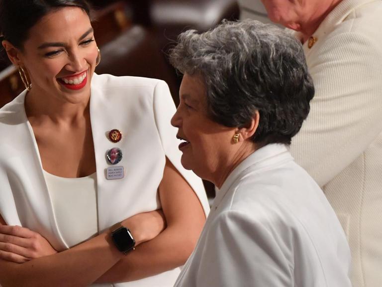 Die demokratische Kongressabgeordnete Alexandria Ocasio-Cortez lacht, als sie mit Kolleginnen spricht - alle in Weiß gekleidet