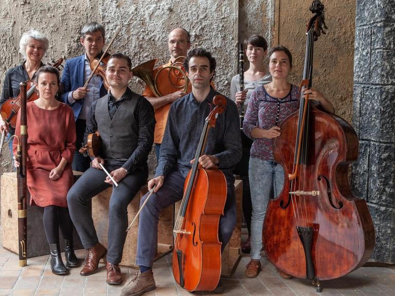 Das Ensemble Anima Eterna Brugge posiert mit Instrumenten vor einer Steinwand
