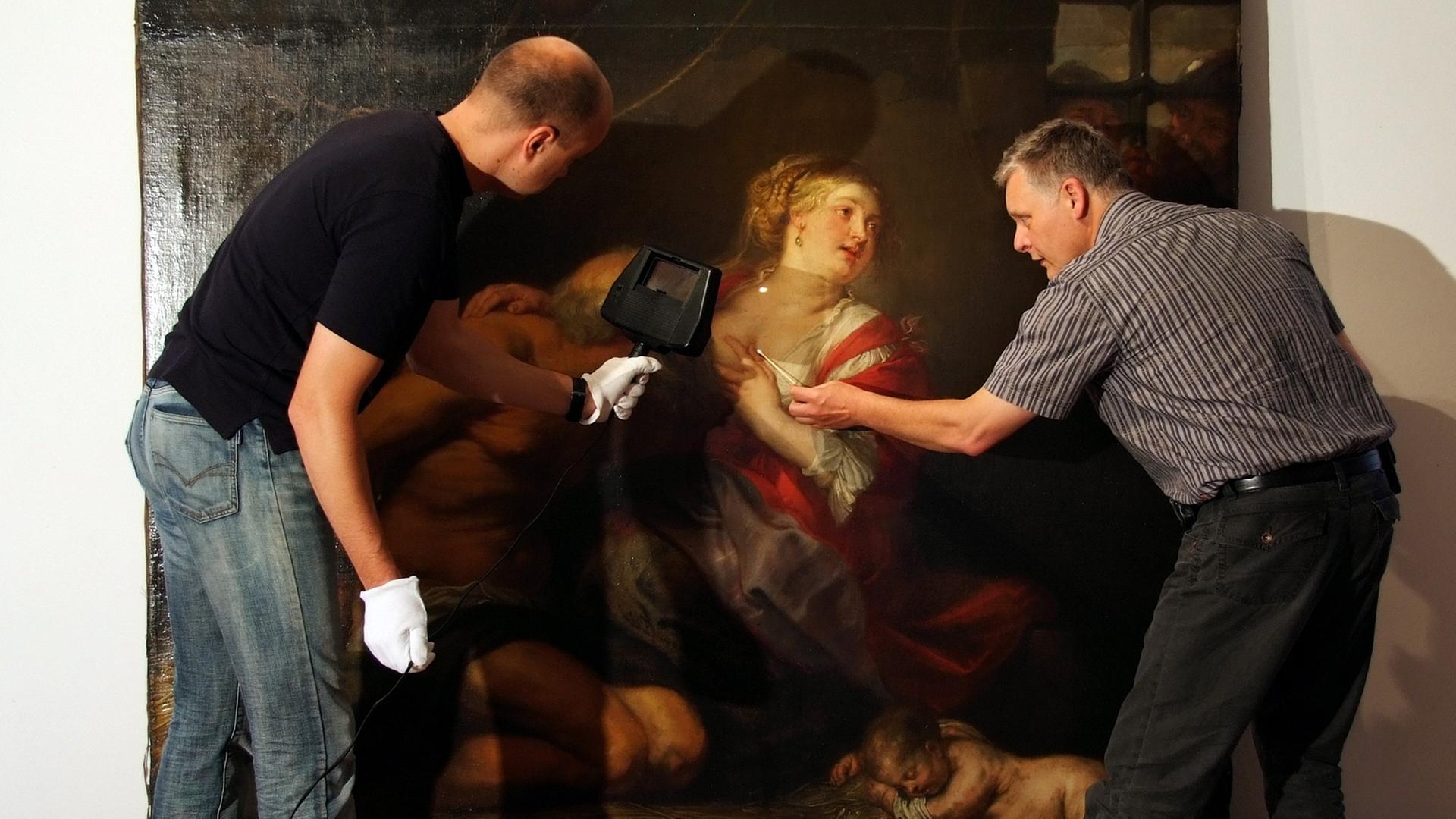 Zwei Restauratoren vor dem Gemälde "Caritas Romana" von Peter Paul Rubens.