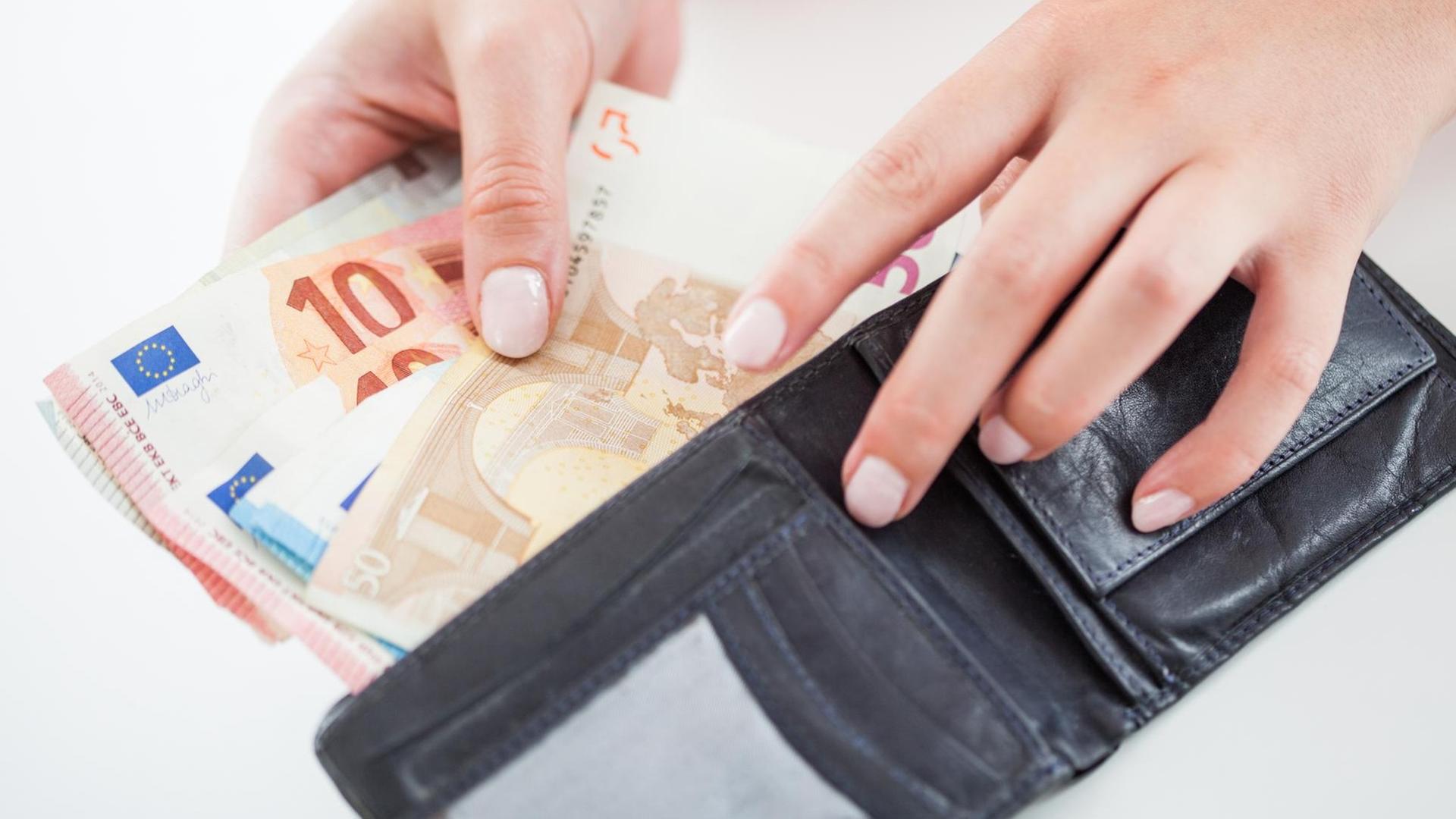Eine Hand nimmt Geld aus einer Geld-Börse. Eine Hand nimmt Geld aus einer Geld-Börse.
