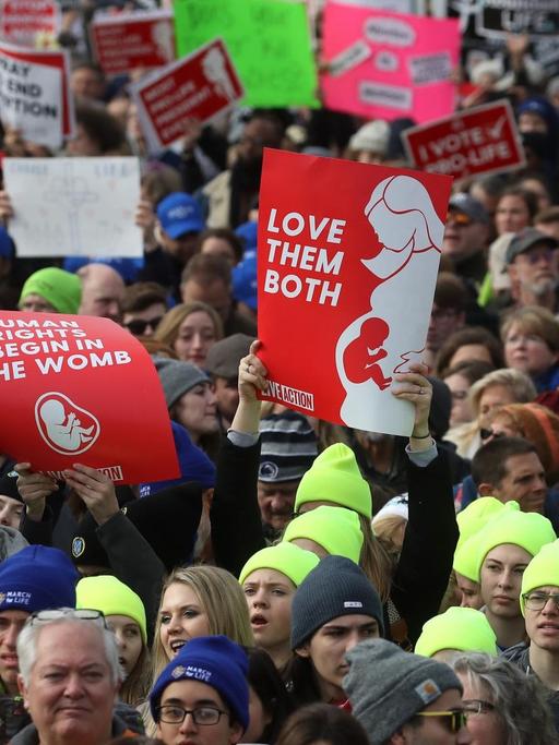 Blick auf eine Demonstration. Die Demonstrantinnen halten Banner, die sich gegen Abtreibung aussprechen.