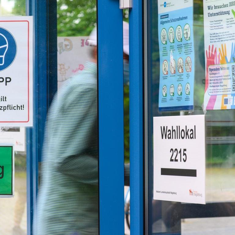 Ein Wähler in Magdeburg betritt ein Wahllokal. Zu sehen ist außerdem ein Schild mit der Aufforderung, Maske zu tragen. 