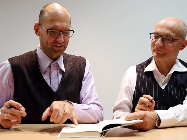 Frank Heibert und Hinrich Schmidt-Henkel sitzen bei einer Lesung in Berlin am 15.11.2016 an einem Tisch