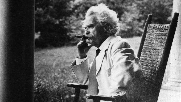Mark Twain sitzt in einem Schaukelstuhl und raucht Zigarre, eine Aufnahme aus dem Jahr ca. 1908 Mark Twain sitzt in einem Schaukelstuhl und raucht Zigarre, eine Aufnahme aus dem Jahr ca. 1908
