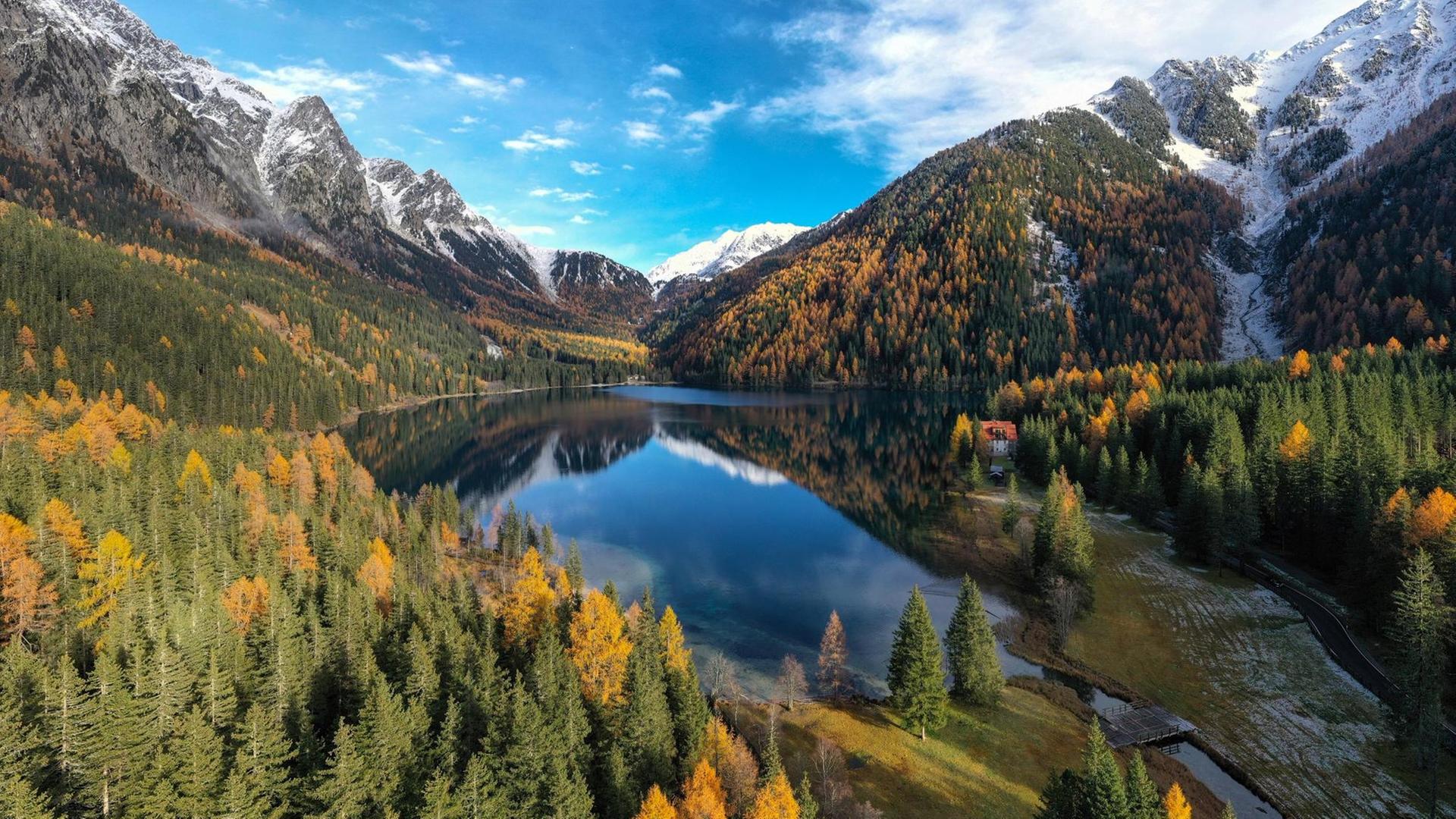 Abendliche Panoramaansicht auf den Antholzer See, links und rechts rahmen Berggipfel den See. Abendliche Panoramaansicht auf den Antholzer See, links und rechts rahmen Berggipfel den See.