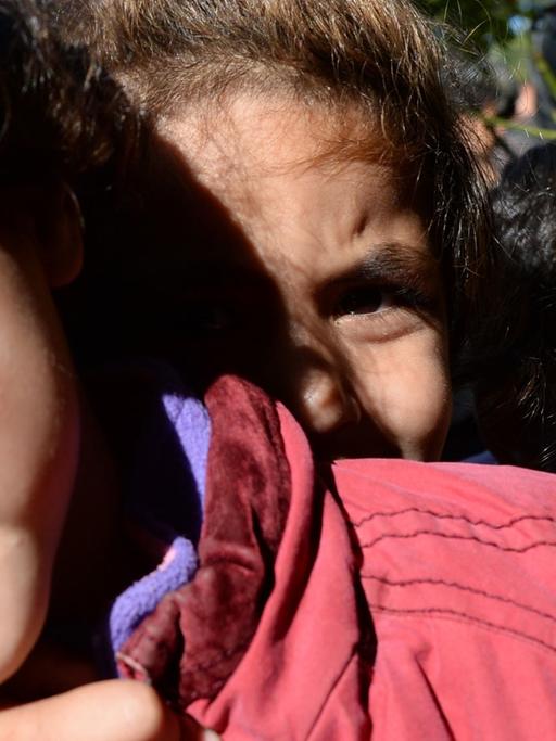 Drei Flüchtlingskinder blicken eng aneinandergedrängt in die Kamera.