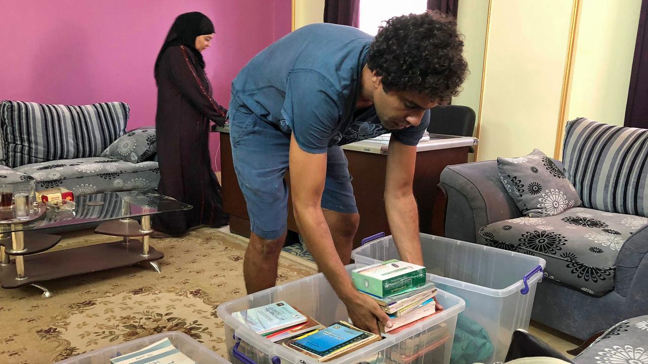 Omar Amin bei der Abholung von Büchern, eine verschleierte Frau ist im Hintergrund zu sehen