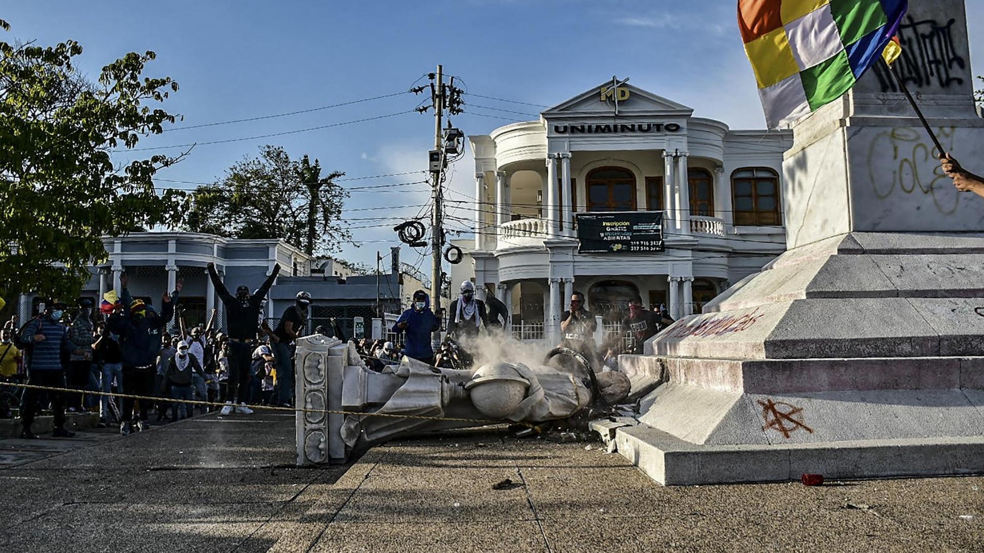Demonstranten stehen jubelnd neben einer gestürzten Kolumbus-Statur im kolumbianischen Barranquilla. Demonstranten stehen jubelnd neben einer gestürzten Kolumbus-Statur im kolumbianischen Barranquilla.
