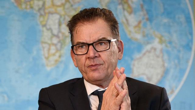 Bundesentwicklungsminister Gerd Müller sitzt vor einer Weltkarte