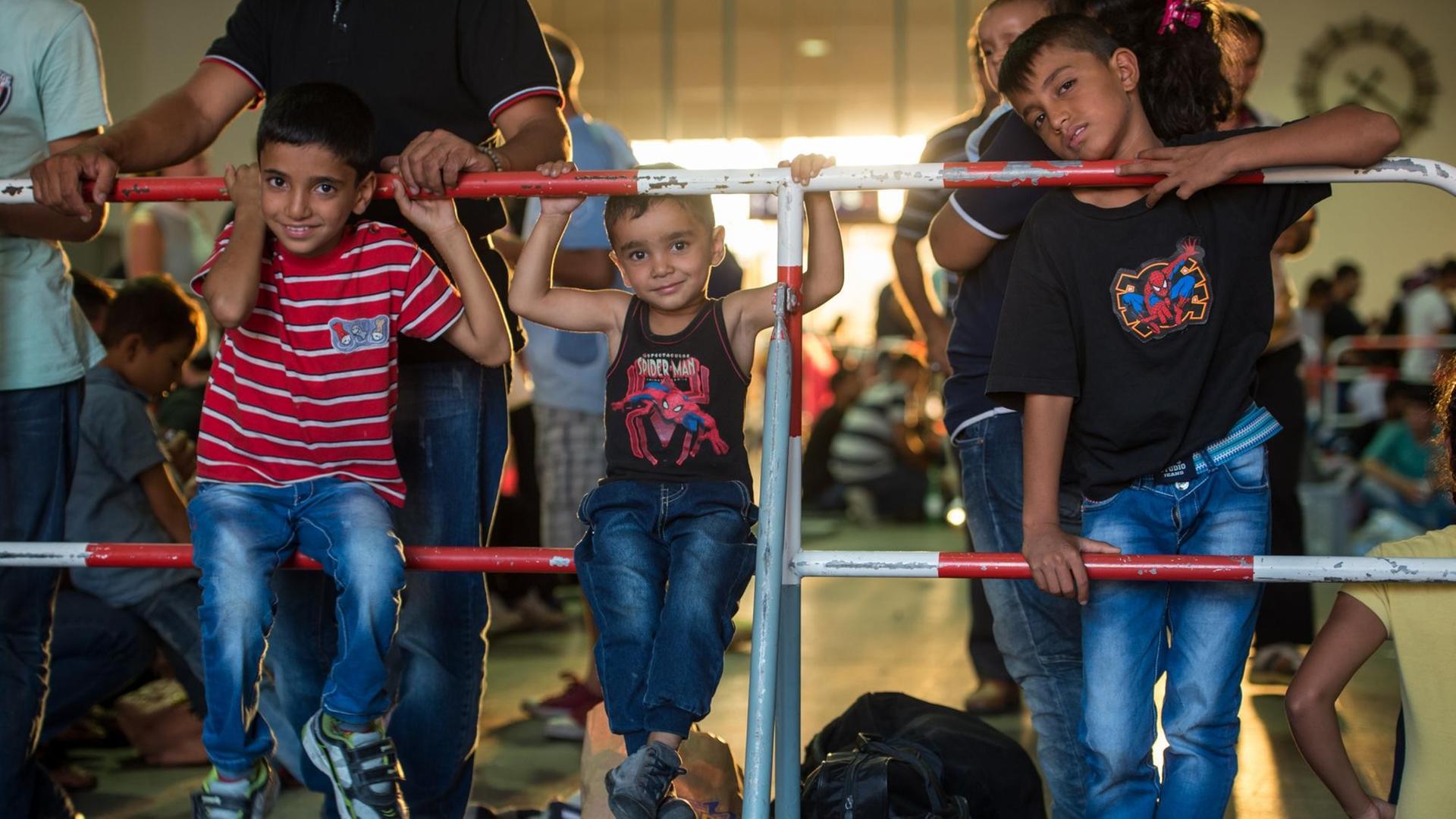 Drei minderjährige Jungen hocken auf einem Absperrgitter. Drei minderjährige Jungen hocken auf einem Absperrgitter.