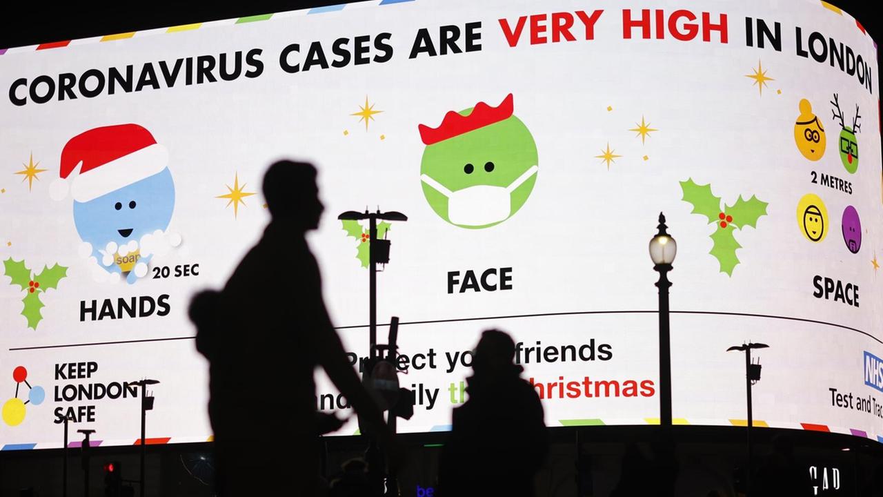 Fußgänger in London laufen an einer digitalen Anzeigentafel vorbei, auf der "Coronavirus-Fälle in London sehr hoch" steht Fußgänger in London laufen an einer digitalen Anzeigentafel vorbei, auf der "Coronavirus-Fälle in London sehr hoch" steht