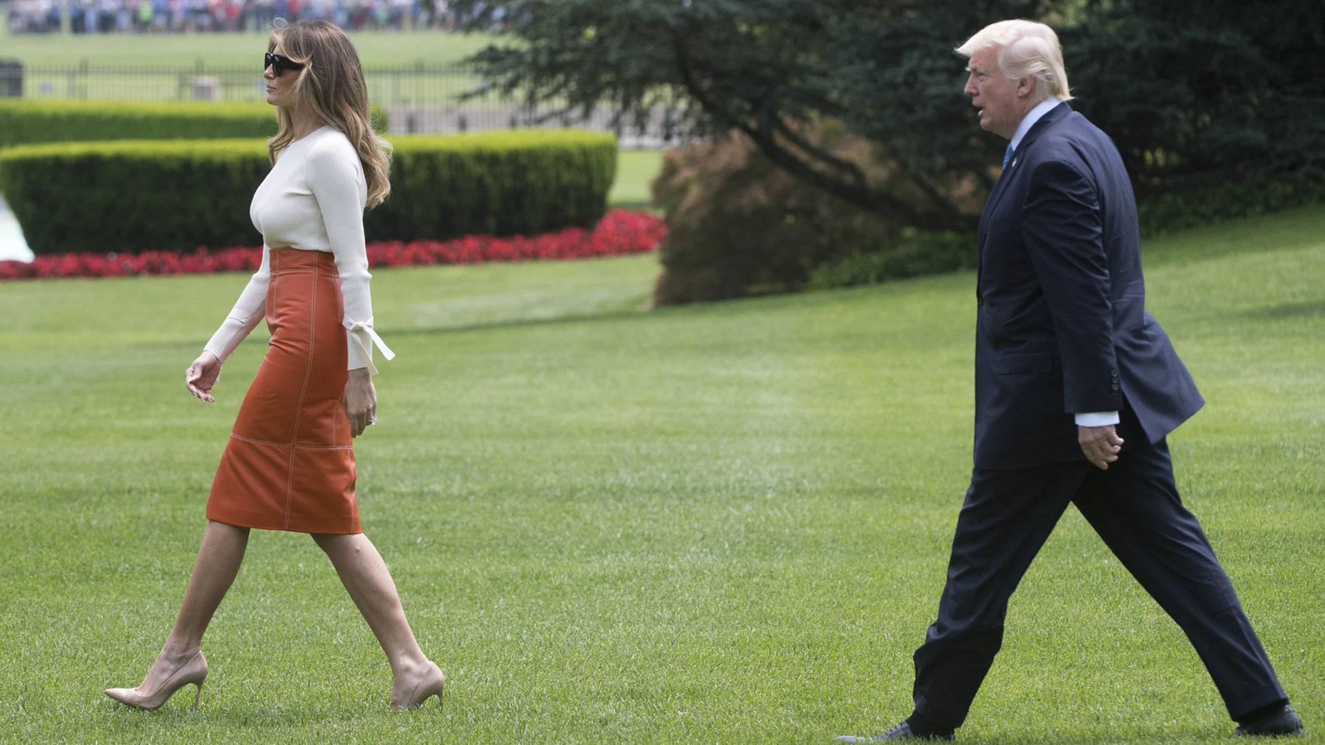 US-Präsident Donald Trump läuft hinter seiner Frau Melania auf dem Rasen des Weißen Hauses hinterher.
