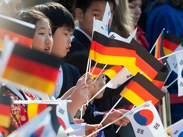 Schulkinder begrüßen am 26.03.2014 am Schloss Bellevue in Berlin die südkoreanische Präsidentin Park mit Papierflaggen Südkoreas und Deutschlands.