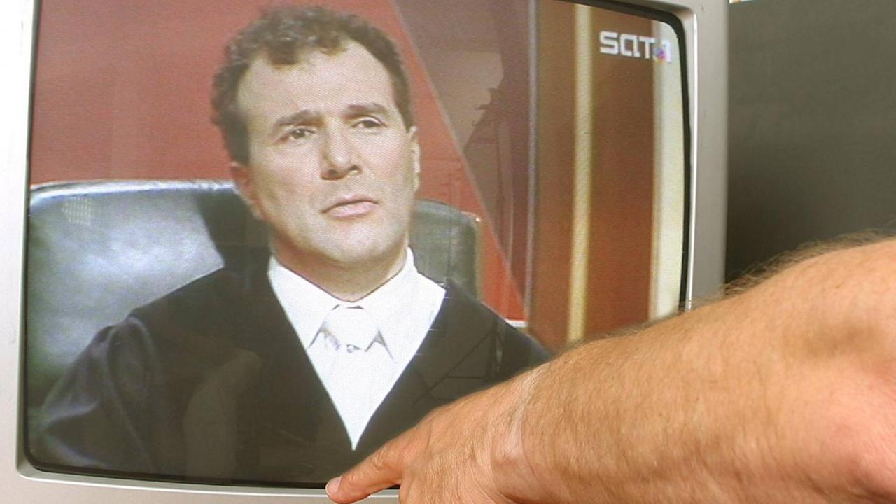 Finger zeigt auf den Ausschalter eines Fernsehers in dem die SAT1-Fernsehsendung -Richter Alexander Hold läuft. Finger zeigt auf den Ausschalter eines Fernsehers in dem die SAT1-Fernsehsendung -Richter Alexander Hold läuft.