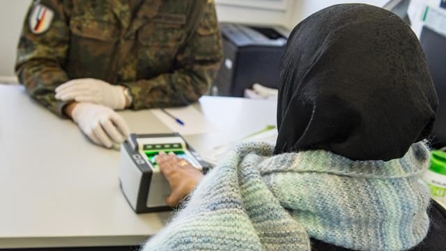 Ein Soldat nimmt einen Fingerabdruck eines Flüchtlings in Erding, Bayern.