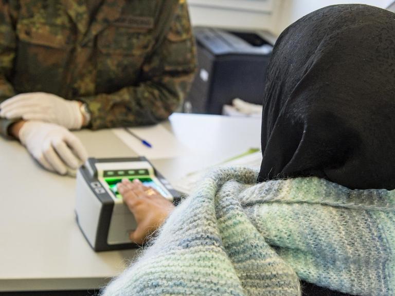 Ein Soldat nimmt einen Fingerabdruck eines Flüchtlings in Erding, Bayern.