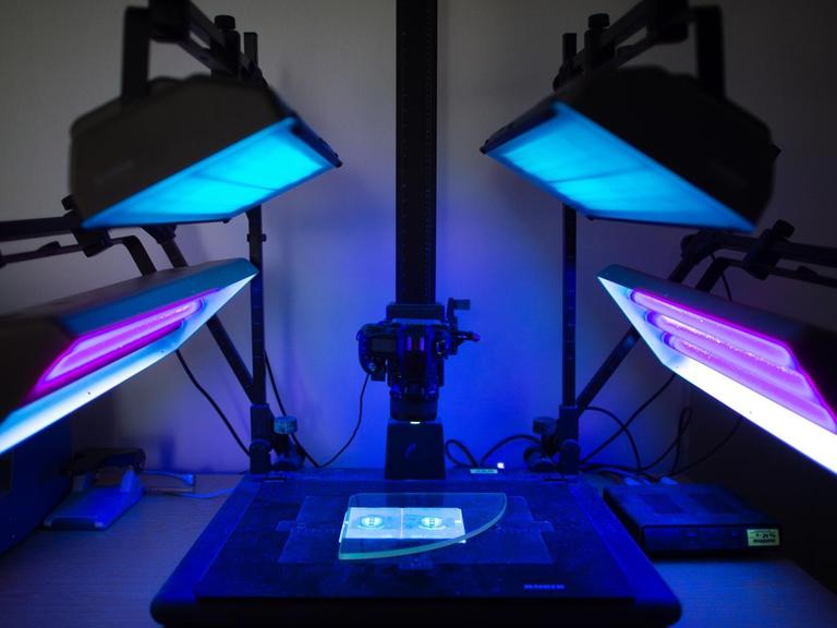 Ein Ausweis liegt in einem Labor der Kriminaltechnik in einer Vorrichtung zum Fotografieren von Ausweisen unter UV-Licht-Bestrahlung. Durch die Ultraviolettstrahlung werden bei einem echten Ausweis spezielle Sicherheitsmerkmale sichtbar.