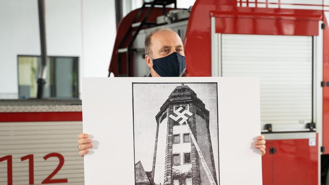 Der Leiter der Mannheimer Feuerwehr, Leitender Branddirektor Karlheinz Gremm, zeigt ein historisches Foto der Alten Feuerwache in Mannheim mit einem Hakenkreuz aus der NS-Zeit.