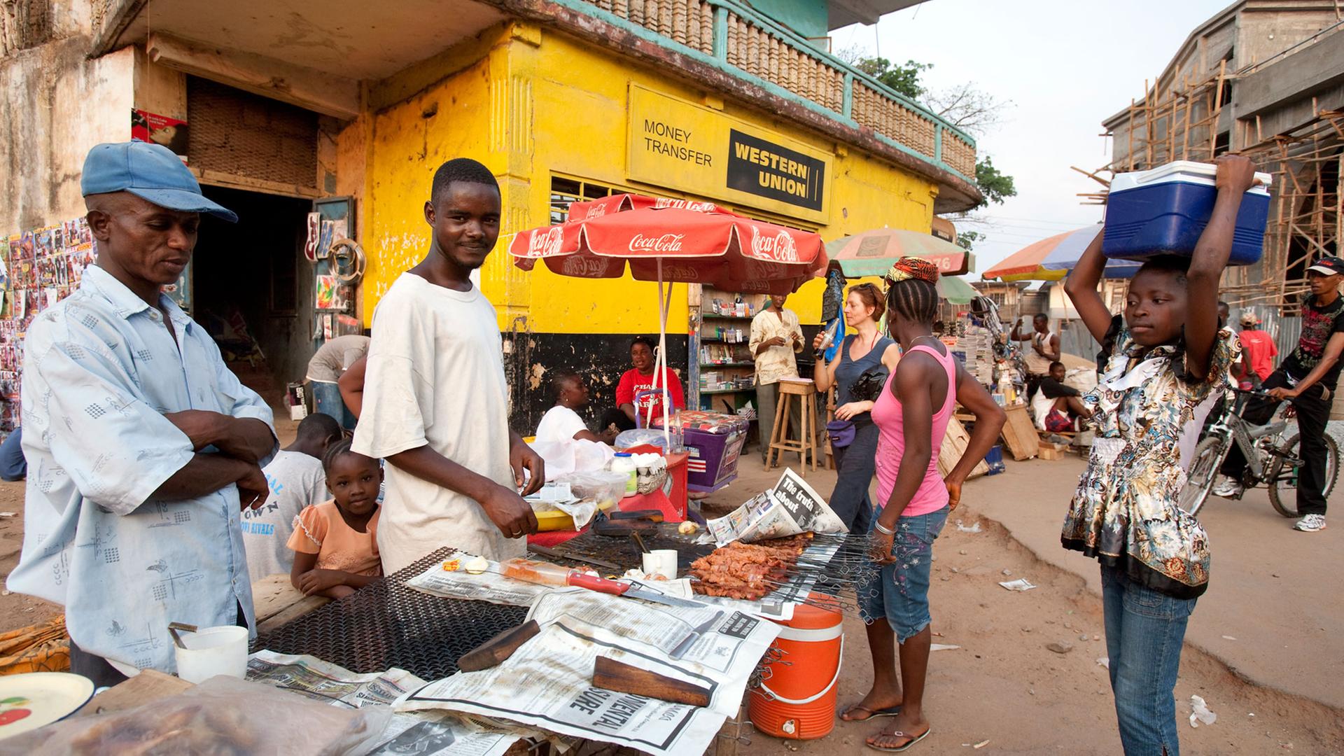 Straßenszene in Makeni, einer Stadt im Nordosten von Sierra Leone - Straßenhändler bieten vor einem Büro von Western Union ihre Waren an. Straßenszene in Makeni, einer Stadt im Nordosten von Sierra Leone - Straßenhändler bieten vor einem Büro von Western Union ihre Waren an.