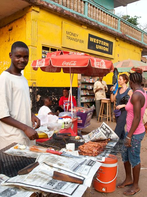 Straßenszene in Makeni, einer Stadt im Nordosten von Sierra Leone - Straßenhändler bieten vor einem Büro von Western Union ihre Waren an.