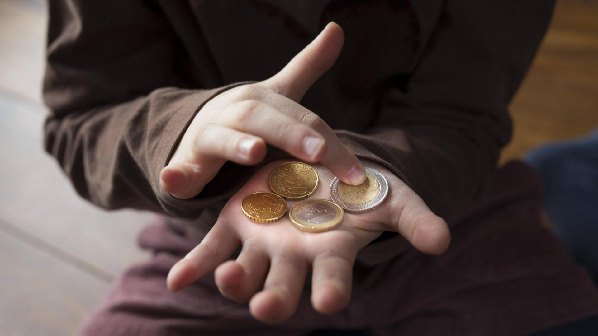 Ein Kind, dessen Gesicht man nicht sieht, zählt sein Taschengeld auf der ausgestreckten Hand. Ein Kind, dessen Gesicht man nicht sieht, zählt sein Taschengeld auf der ausgestreckten Hand.