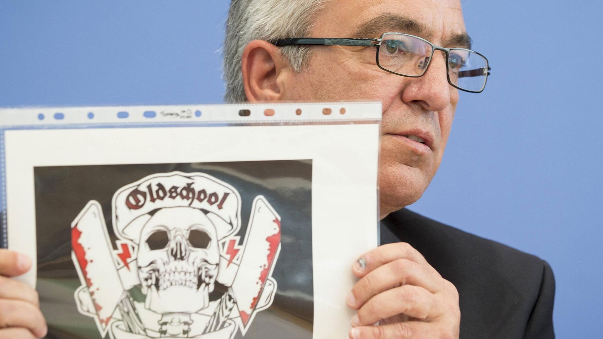 Der Vorsitzende der Innenministerkonferenz, Roger Lewentz, zeigt das Logo der rechtsextremen Gruppierung "Oldschool Society" Der Vorsitzende der Innenministerkonferenz, Roger Lewentz, zeigt das Logo der rechtsextremen Gruppierung "Oldschool Society"