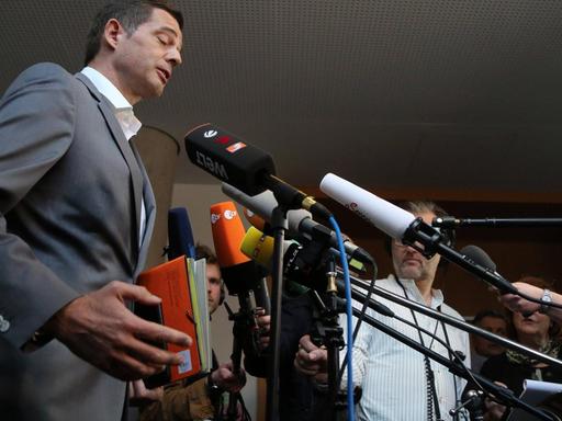 Thüringens CDU-Fraktionschef Mike Mohring steht links vor vielen Mikrofonen von Journalisten und hält eine rote Mappe in der Hand