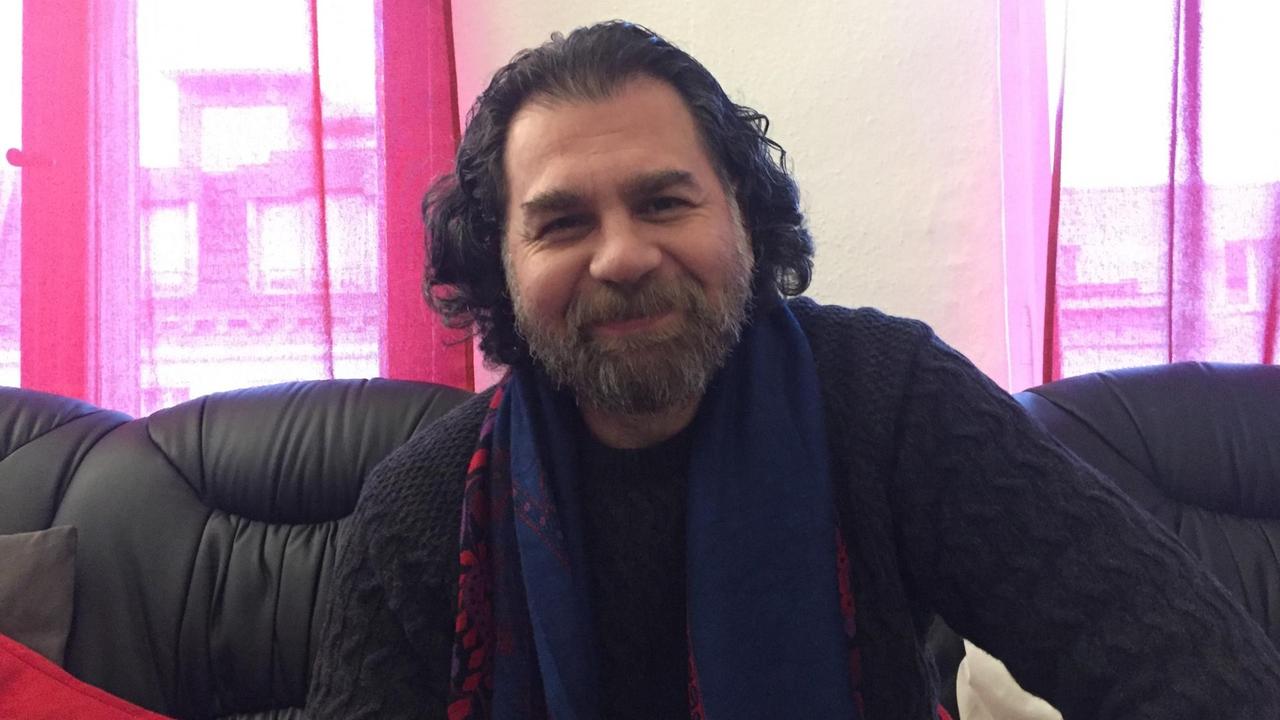 Der syrische Schriftsteller Ibrahim Aljabin sitzt locker auf einem Sofa. Der syrische Schriftsteller Ibrahim Aljabin sitzt locker auf einem Sofa.