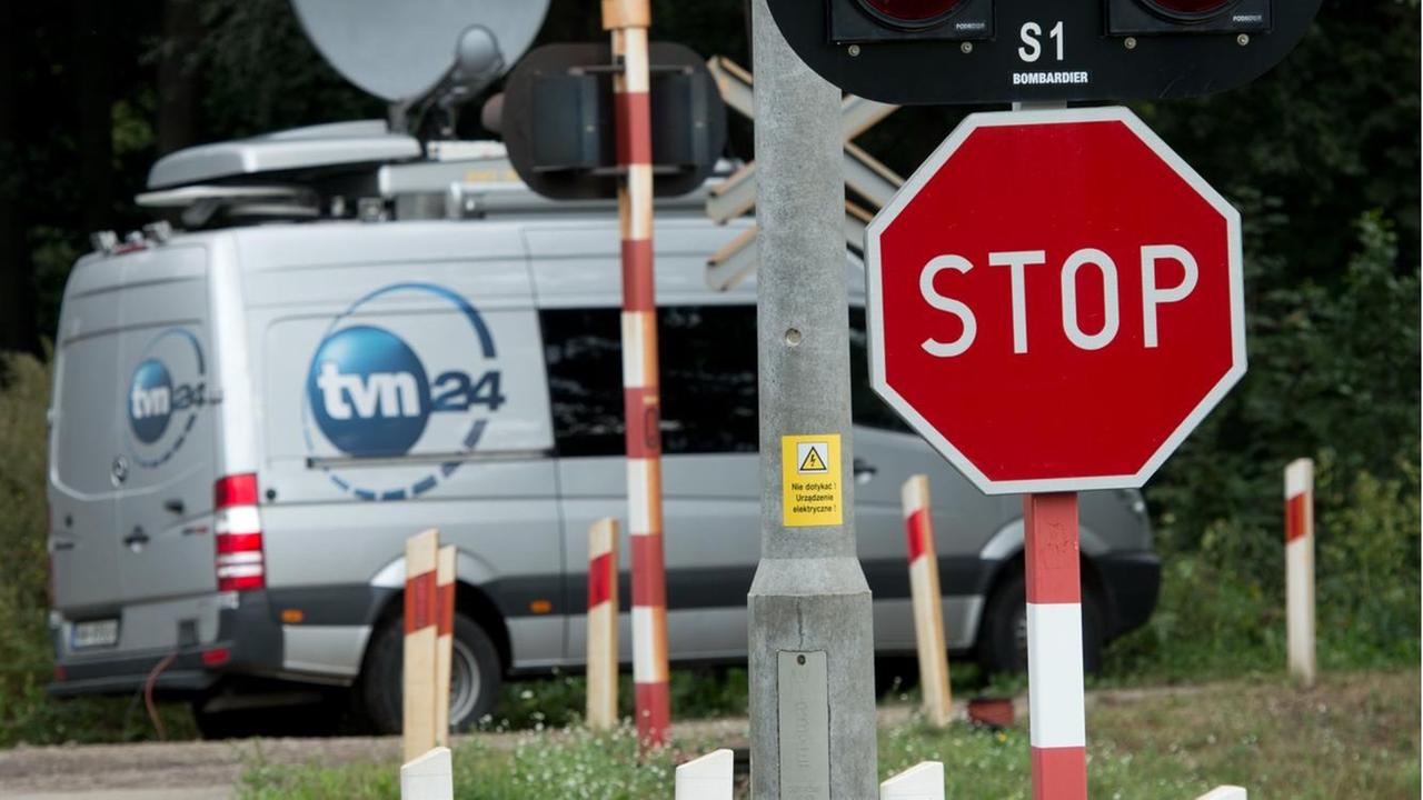 Ein Lieferwagen von "TVN24" hinter einem Bahnübergang. Ein Lieferwagen von "TVN24" hinter einem Bahnübergang.
