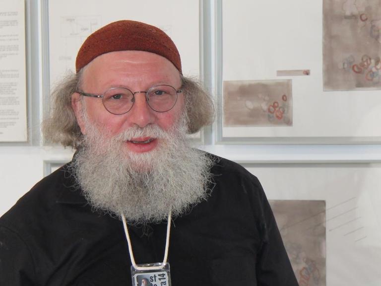 Der Komponist Jakob Ullmann steht in einer Galerie vor seinen bildnerischen Arbeiten