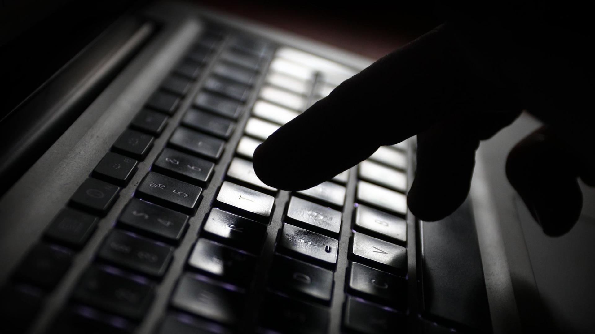 Der Schatten einer Hand ist über einer Computer-Tastatur zu sehen. Der Schatten einer Hand ist über einer Computer-Tastatur zu sehen.