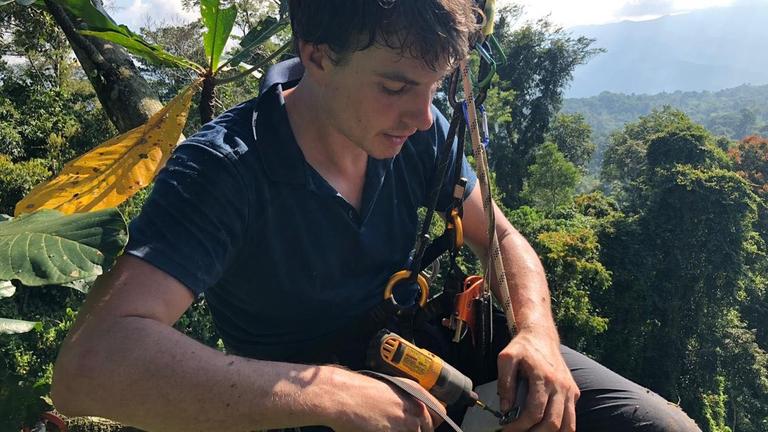 Der US-Physiker Topher White hängt an einem Seil und Gurt in den Baumkronen im tropischen Regenwald, um einen Akustik-Sensor zu montieren
