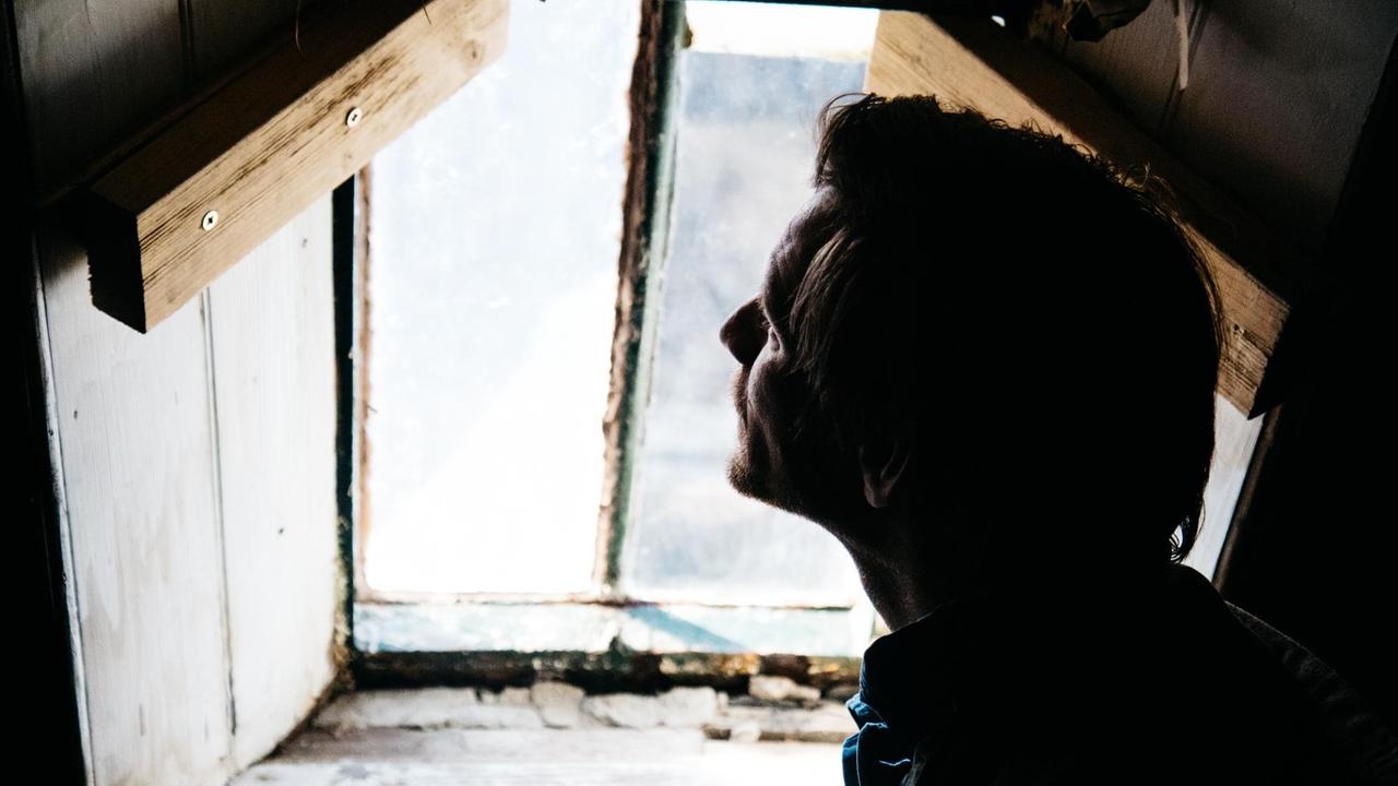 Das Profil eines Mannes ist im Gegenlicht in einer Mountain Bothy zu sehen - einer Schutzhütte in den schottischen Highlands. Das Profil eines Mannes ist im Gegenlicht in einer Mountain Bothy zu sehen - einer Schutzhütte in den schottischen Highlands.