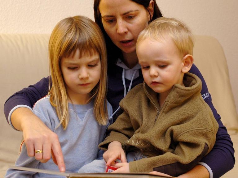 Eine Mutter liest ihren Kindern aus einem Buch vor
