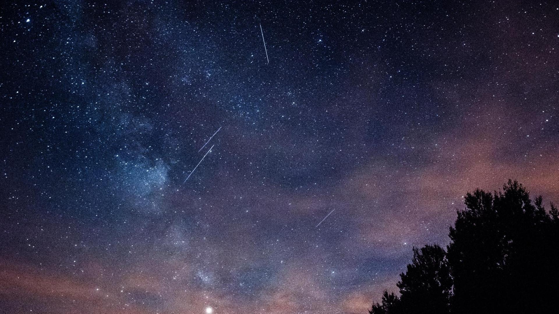 Ein imposanter sternklarer Himmel in der Nacht mit drei Sternschuppen. Ein imposanter sternklarer Himmel in der Nacht mit drei Sternschuppen.