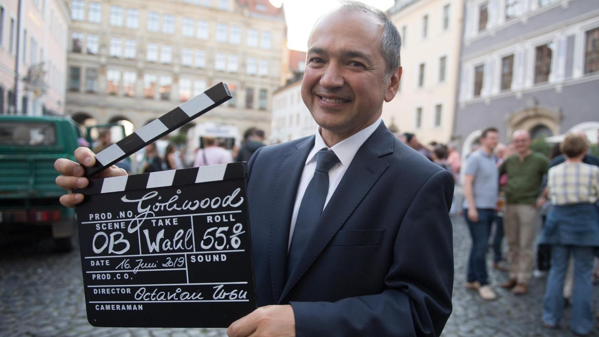 Das Bild zeigt den neuen Oberbürgermeister von Görlitz: Octavian Ursu (CDU) hat sich gegen die AfD durchgesetzt. Er steht auf einer Wahlparty seiner Partei mit einer Filmklappe vor dem Rathaus auf dem Untermarkt. Das Bild zeigt den neuen Oberbürgermeister von Görlitz: Octavian Ursu (CDU) hat sich gegen die AfD durchgesetzt. Er steht auf einer Wahlparty seiner Partei mit einer Filmklappe vor dem Rathaus auf dem Untermarkt.