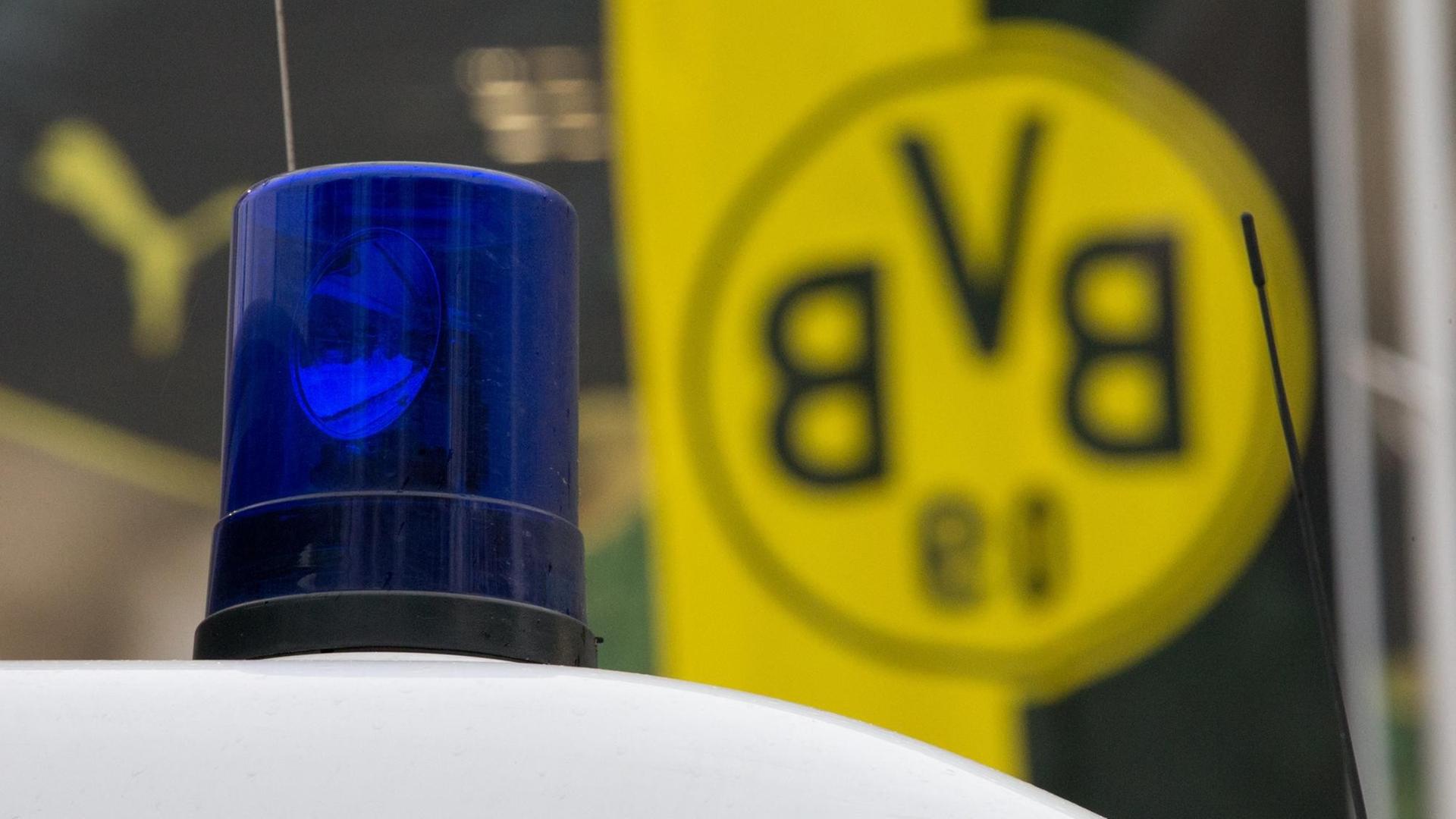 Das Blaulicht eines Polizeiwagens vor einer Fahne mit dem BVB-Logo. Das Blaulicht eines Polizeiwagens vor einer Fahne mit dem BVB-Logo.
