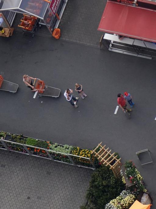 Kunden eines Baumarktes stehen vor dem Eingang mit Abstand in einer Schlange. Zur Eindämmung des Coronavirus hat NRW alle Ansammlungen ab drei Personen in der Öffentlichkeit verboten.