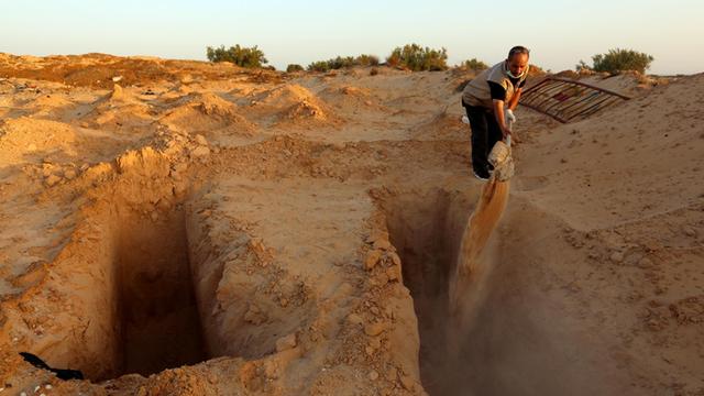 Der ehemalige Fischer Chamseddine Marzoug gräbt ein Grab für einen weiteren Migranten auf dem behelfsmäßigen "Friedhof der Unbekannten" in Zarzis/ Tunesien