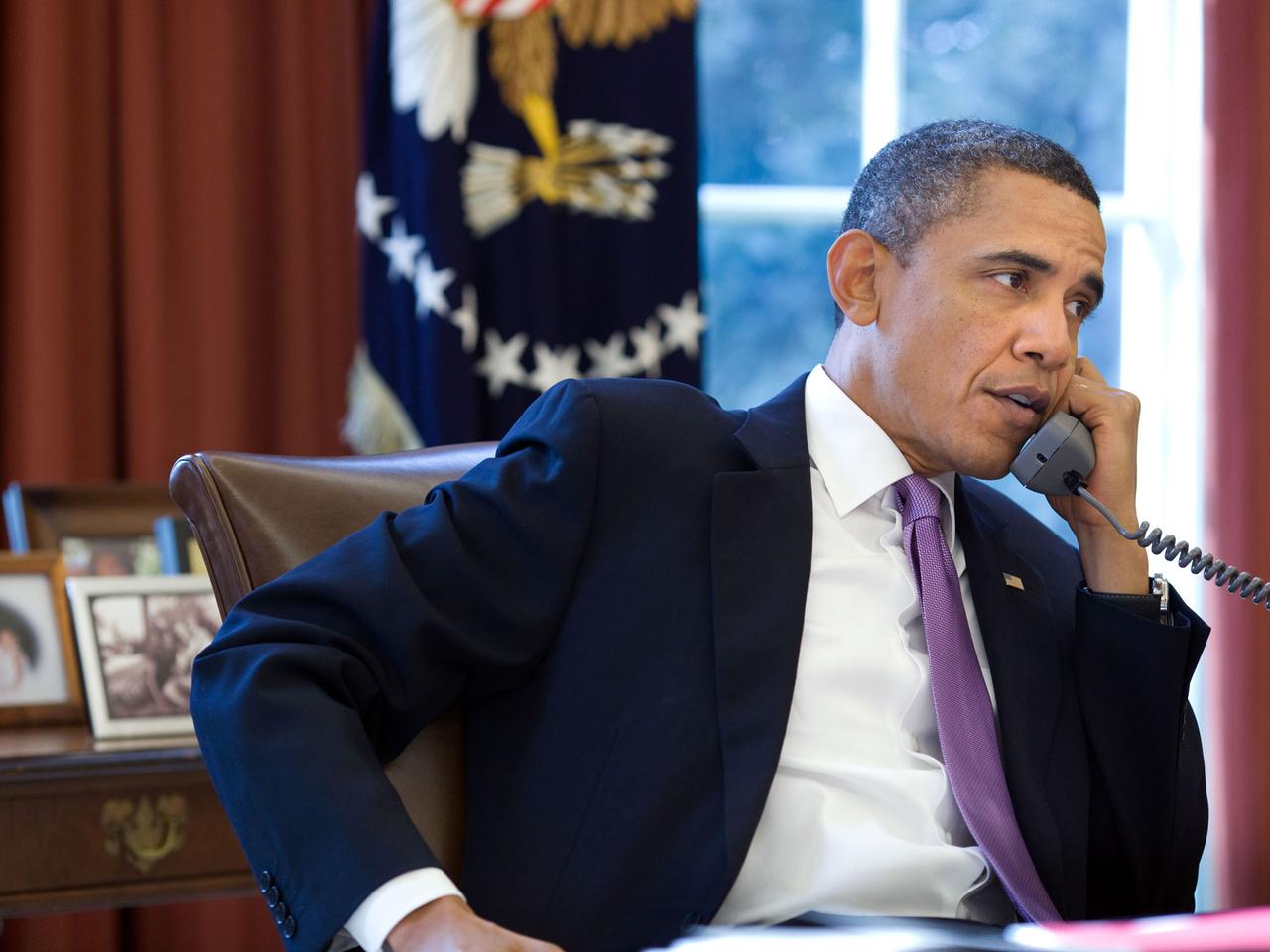 US-Präsident Barack Obama sitzt an seinem Schreibtisch im Oval Office, in der linken Hand hält er den Telefonhörer. US-Präsident Barack Obama sitzt an seinem Schreibtisch im Oval Office, in der linken Hand hält er den Telefonhörer.