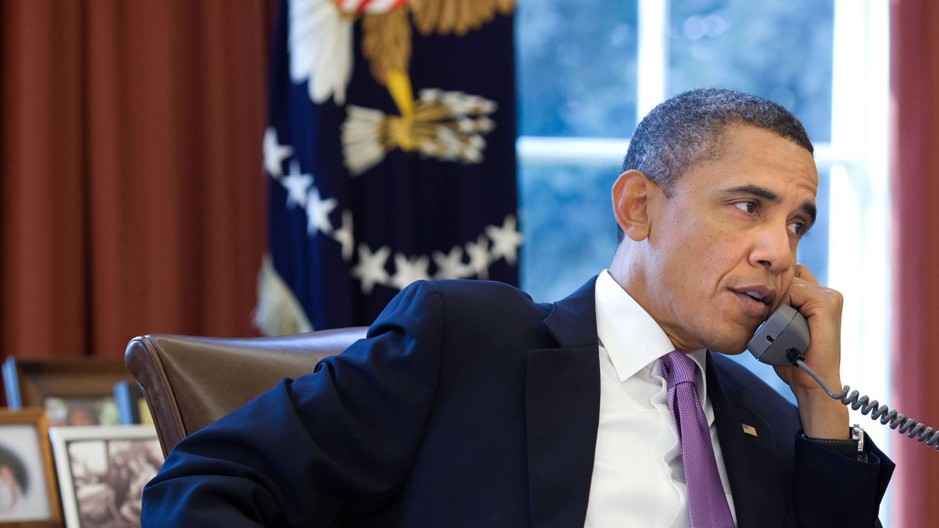 US-Präsident Barack Obama sitzt an seinem Schreibtisch im Oval Office, in der linken Hand hält er den Telefonhörer. US-Präsident Barack Obama sitzt an seinem Schreibtisch im Oval Office, in der linken Hand hält er den Telefonhörer.