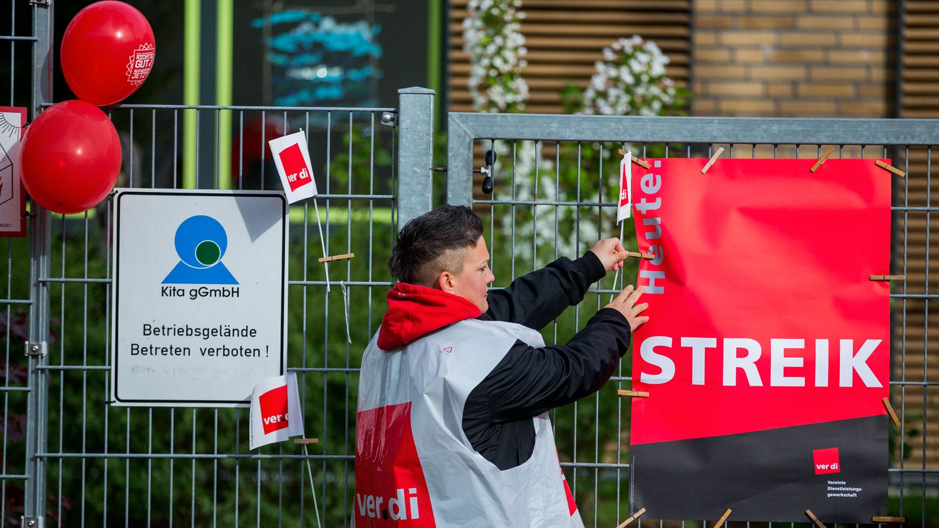 Eine Erzieherin der Kindertagesstätte "Kirschblüte" hängt in Schwerin ein Streik-Plakat an den Eingang der Einrichtung. Eine Erzieherin der Kindertagesstätte "Kirschblüte" hängt in Schwerin ein Streik-Plakat an den Eingang der Einrichtung.