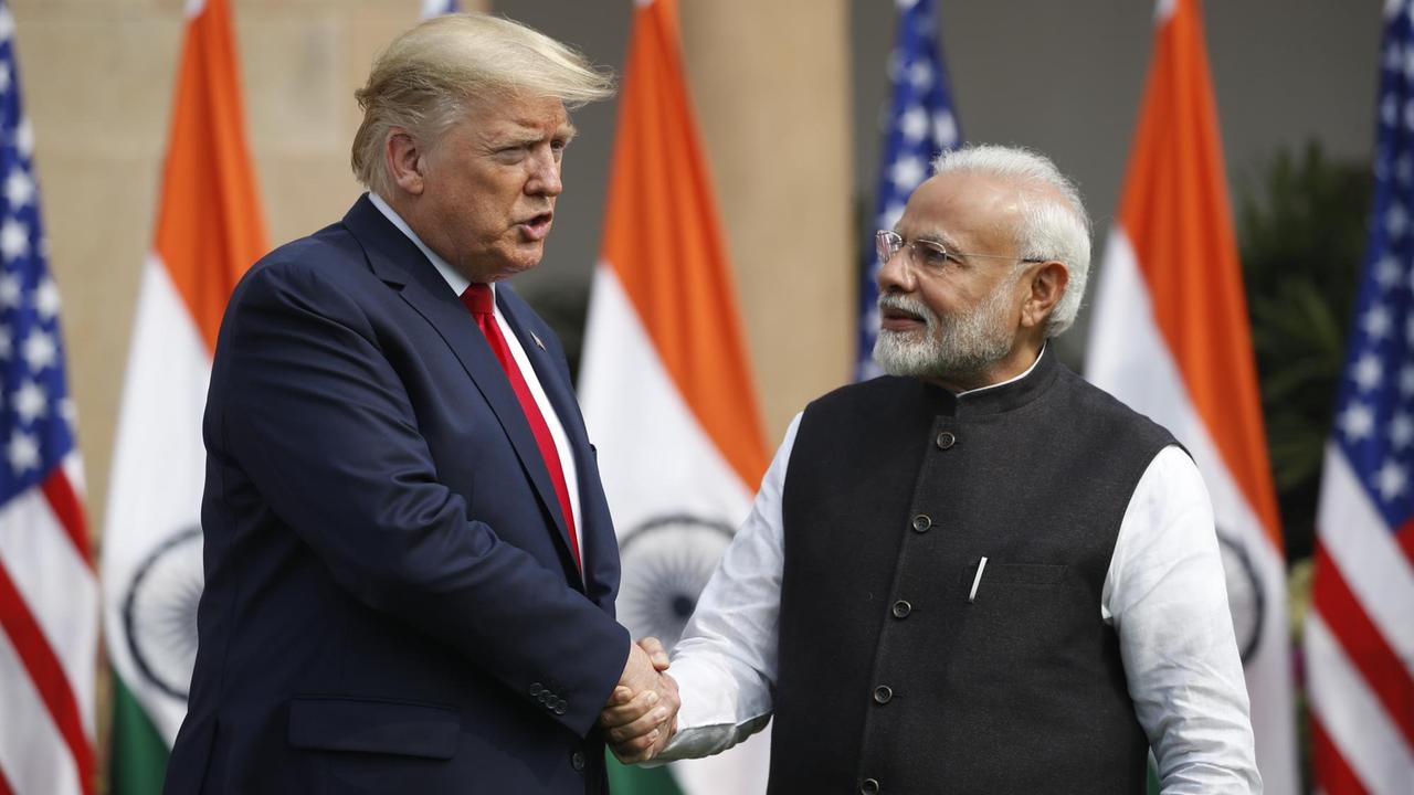 US-Präsident Trump schüttelt dem indischen Premierminister Modi die Hand. Ihnen ihnen die Flaggen der beiden Länder. 