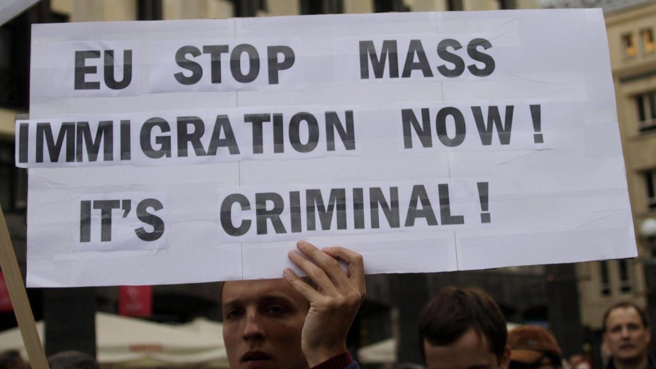 Proteste gegen die EU-Verteilungsquote für Flüchtlinge in Lettlands Hauptstadt Riga. Ein Demonstrant hält ein Schild in die Höhe auf dem steht: "EU stop mass immigration now. It's criminal!" (Auf Deutsch: "EU beende die Masseneinwanderung jetzt. Das ist kriminell!") Proteste gegen die EU-Verteilungsquote für Flüchtlinge in Lettlands Hauptstadt Riga. Ein Demonstrant hält ein Schild in die Höhe auf dem steht: "EU stop mass immigration now. It's criminal!" (Auf Deutsch: "EU beende die Masseneinwanderung jetzt. Das ist kriminell!")